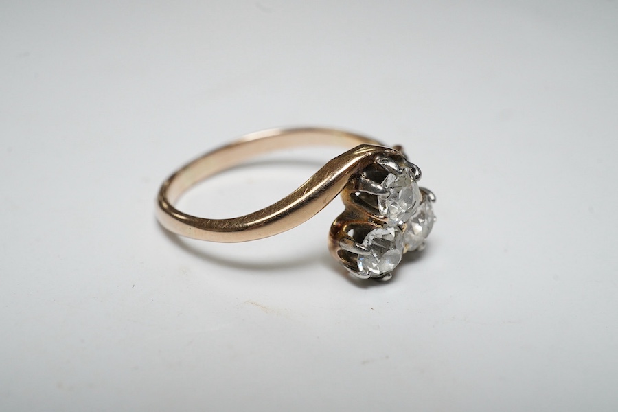 A yellow metal and three stone diamond set crossover ring, with single stone diamond set shoulder, size K, gross weight 2.4 grams. Condition - poor to fair